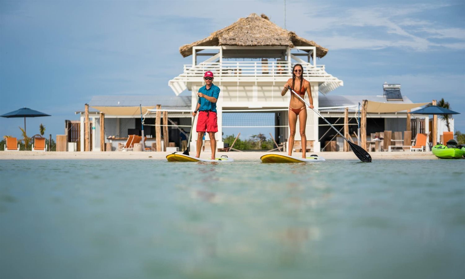 Couple paddleboarding at beach club